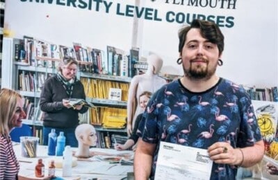 A North Devon College student holding up his grades