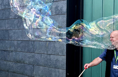 Two people laughing while creating huge bubbles