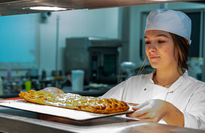 student serving a plate of food onto a hotplate