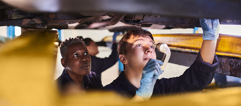 Two people looking under a car