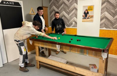 three students playing pool.