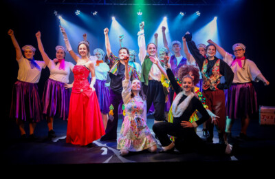 performing arts students posing in costume at the end of a musical performance