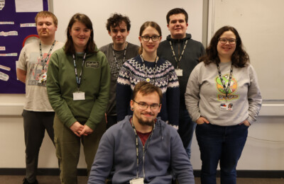 a group of supported internship students standing at the front of the class posing for camera during a lesson