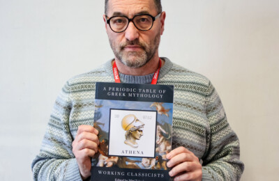 Mike Beer posing to camera with his published work