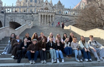 Students sat on steps in front of historic Budapest building